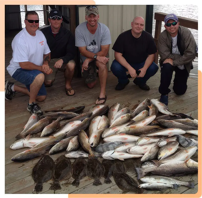 A group of men standing next to a pile of fish.